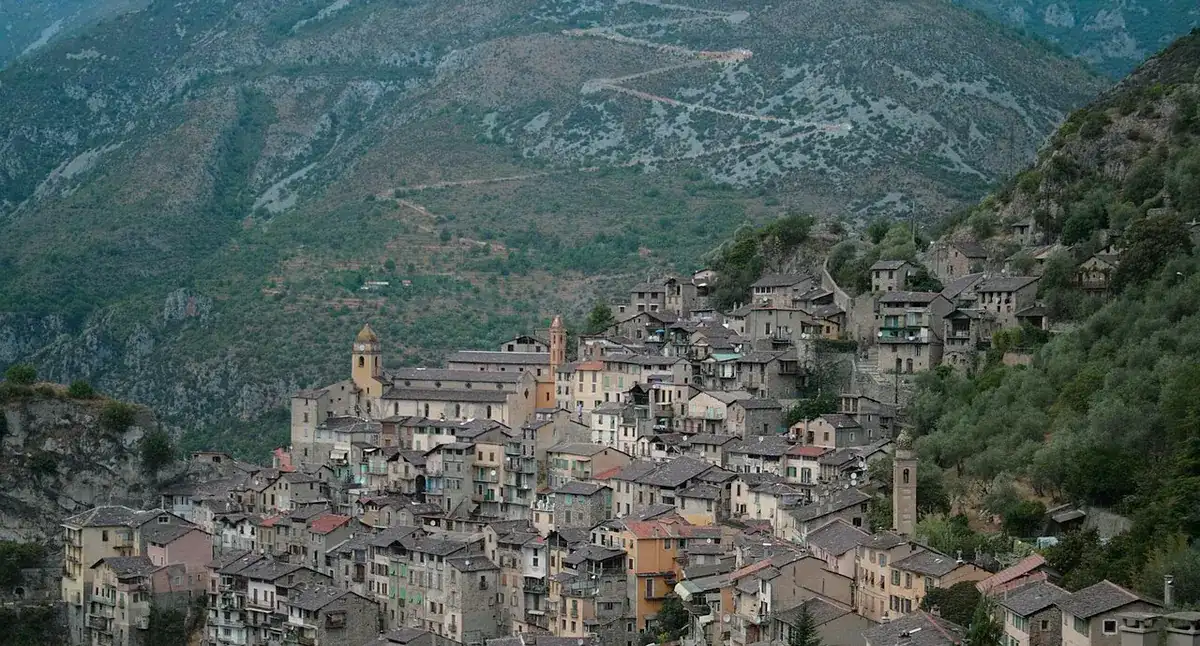 Un village de hautes maisons de pierre grise serrées les unes contre les autres, accroché à flanc de montagne au-dessus d'une vallée profonde, avec ses clochers et ses toits de lauze.